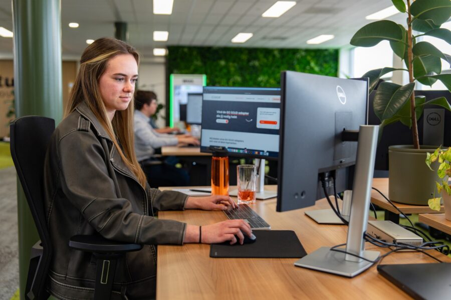 Vrouw werkt geconcentreerd aan webdesign achter een computer in het moderne kantoor van Wux.