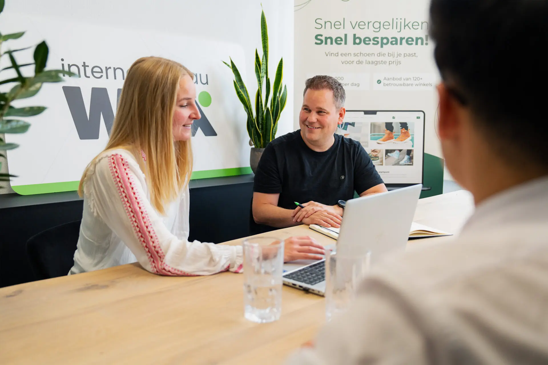 Lachende man en een vrouw zitten aan een bureau in overleg