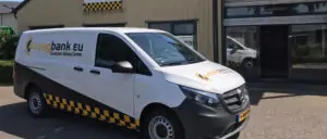 Een witte Mercedes-Benz bedrijfswagen met Airbagbank.eu-logo en zwart-gele belettering, geparkeerd voor een bedrijfspand met bijpassende branding.