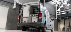 Een bestelwagen met open achterdeuren in een industriële ruimte, waarin een VebaBox-koelunit en opberglades zijn ingebouwd