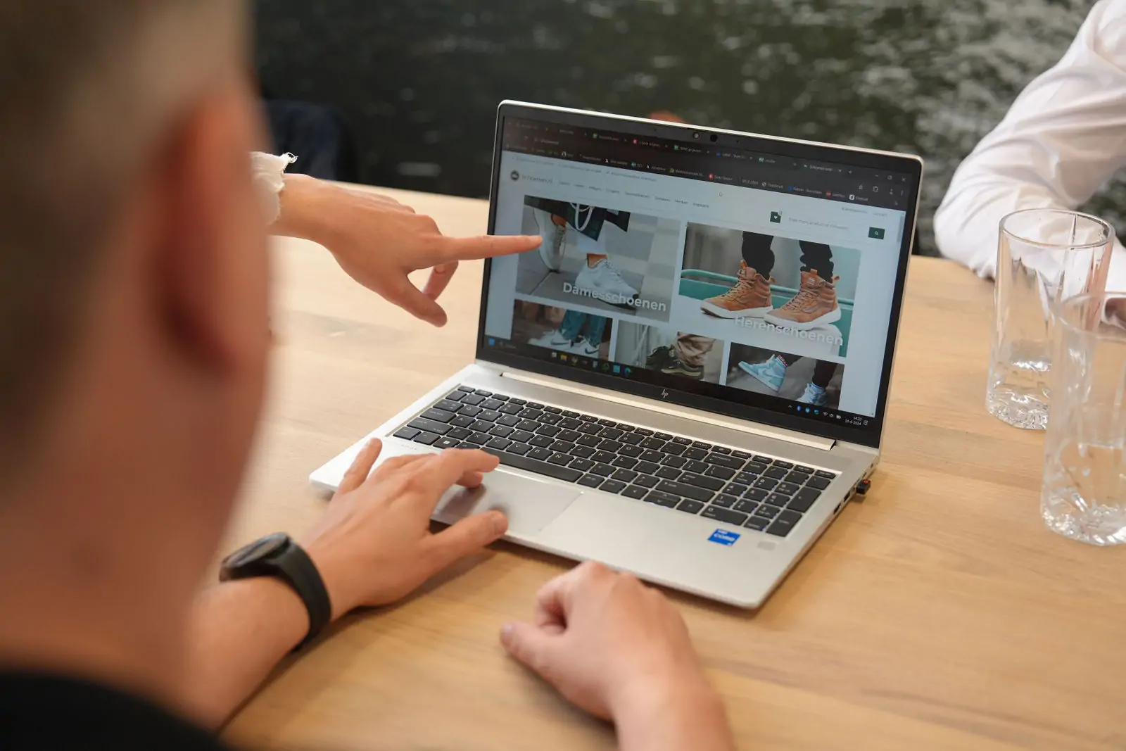 Medewerkers zijn in overleg en een collega wijst naar de laptop