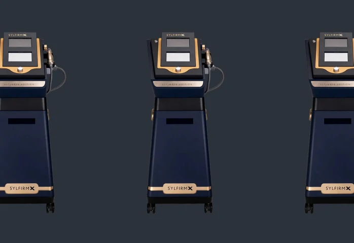 Drie identieke Sylfirm X medische esthetische apparaten op een donkere achtergrond.