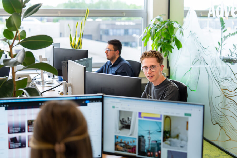 De moderne kantooromgeving van Wux met meerdere medewerkers die achter hun computerschermen werken en daarbij professionele fotografie gebruiken.