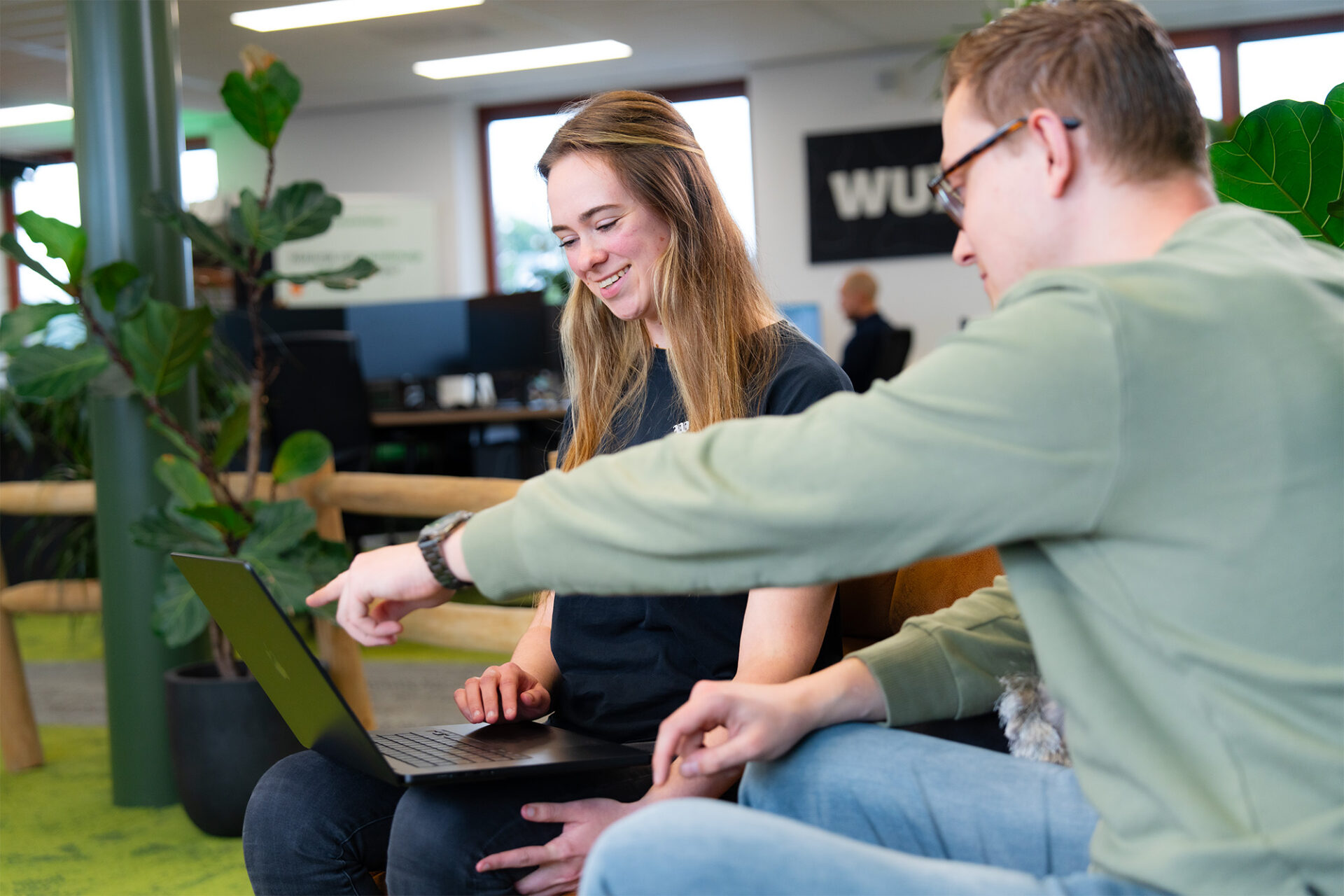 Teamleden bespreken gegenereerde content op een laptop met een glimlach, terwijl AI-tools helpen bij het creëren van effectieve marketingteksten.