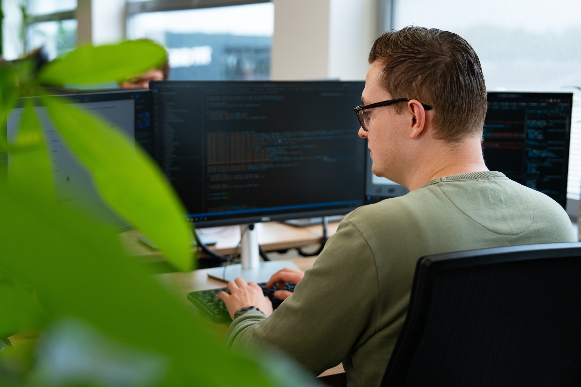 Developer schrijft code op meerdere schermen, gefocust op de balans tussen AI-functionaliteit en ethische richtlijnen zoals privacy, bias en verantwoord datagebruik.
