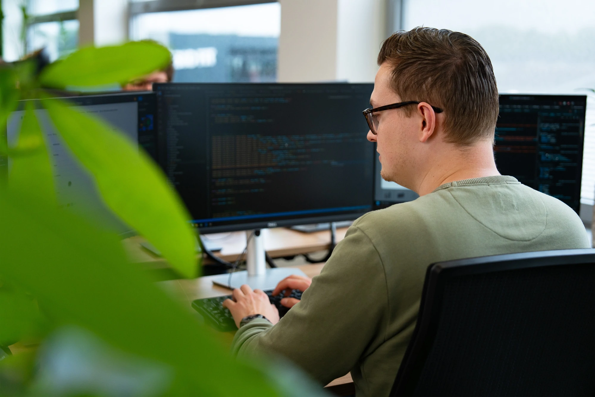 Developer schrijft code op meerdere schermen, gefocust op de balans tussen AI-functionaliteit en ethische richtlijnen zoals privacy, bias en verantwoord datagebruik.