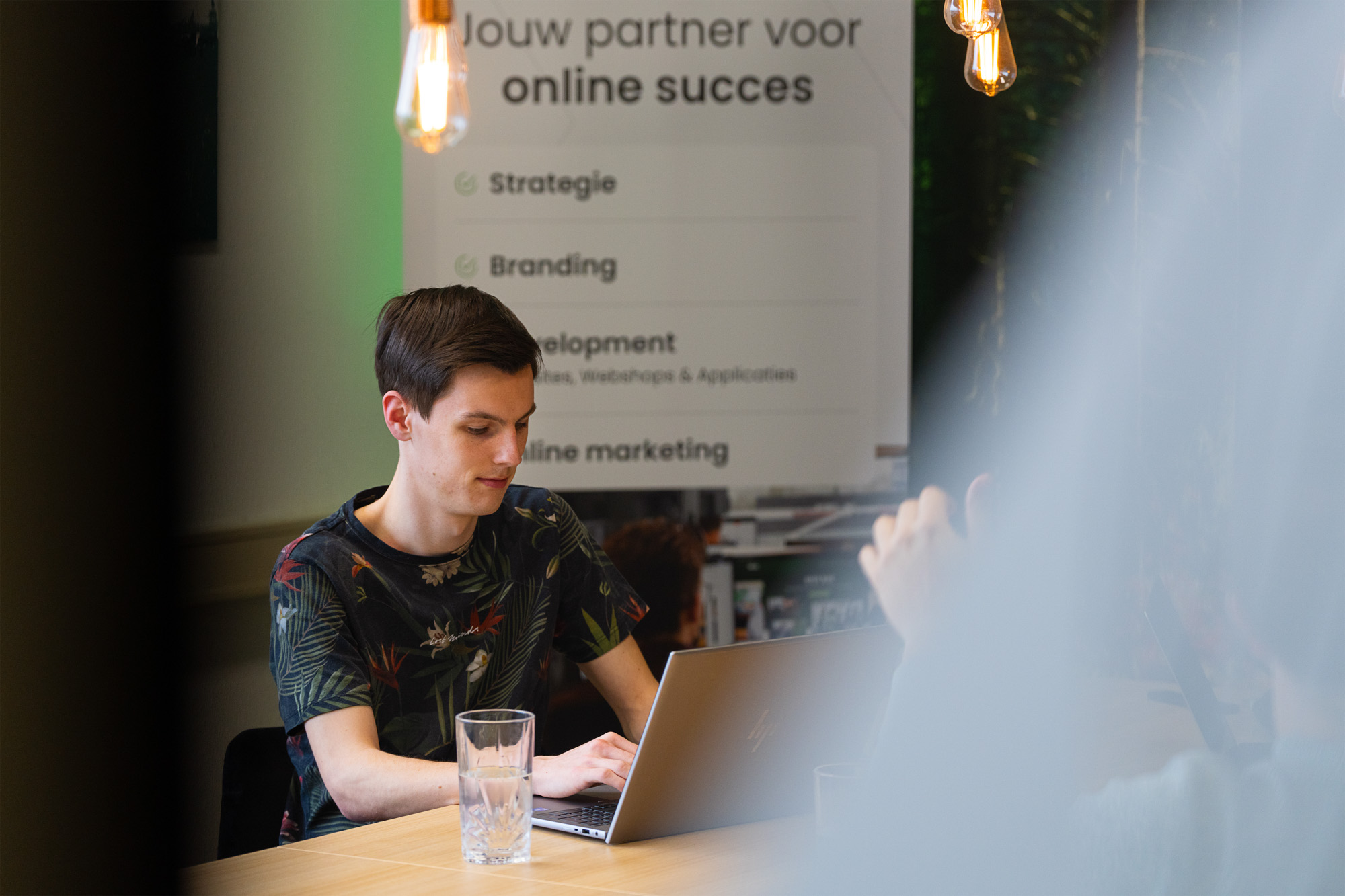 Jonge professional werkt geconcentreerd aan zijn laptop tijdens een overleg over digitale strategieën, waar thema’s als transparantie en ethisch gebruik van AI centraal staan.