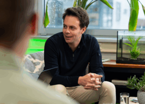 mkb-ondernemer in gesprek met collega's over AI-strategieën tijdens een informele teamsessie op kantoor bij Wux.