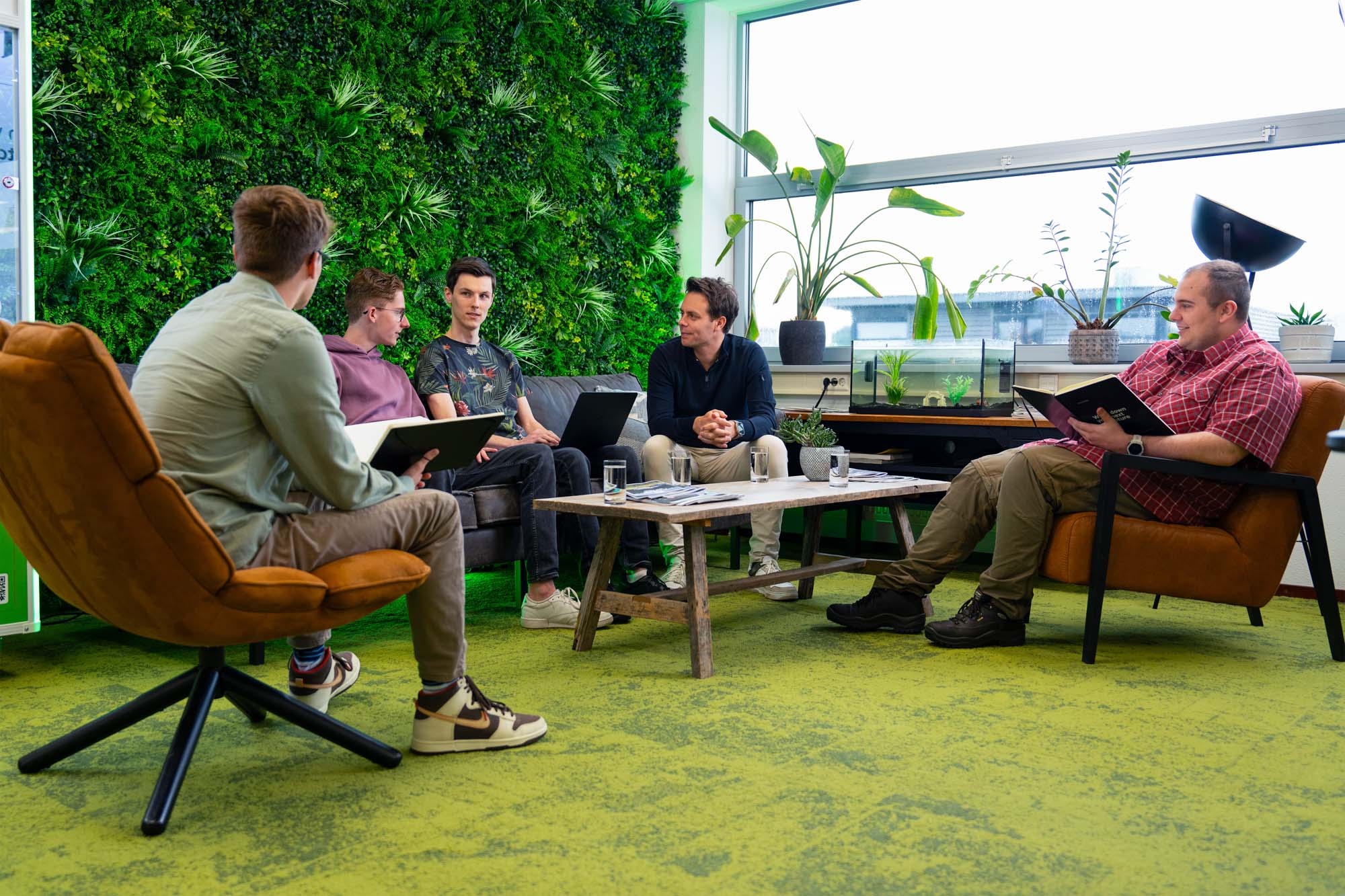Team bespreekt ERP-systemen voor e-commerce tijdens een informele meeting in de kantoorruimte van Wux.