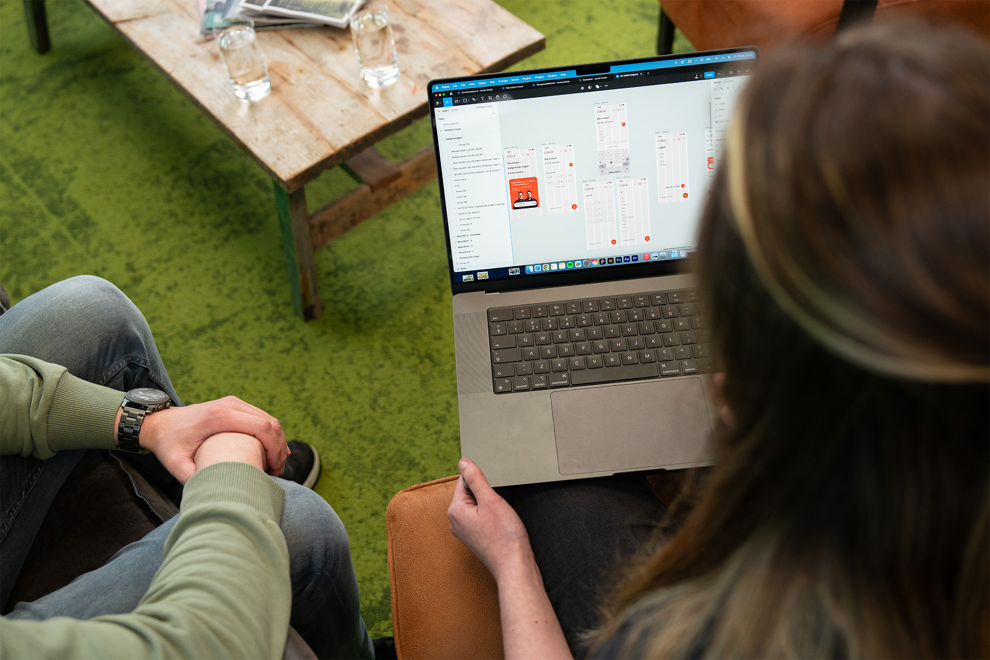 Twee medewerkers van Wux kijken samen naar een laptopscherm met een wireframe-ontwerp in de pagebuilder.