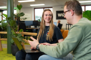 Twee collega’s lachend in gesprek over het maken van effectieve AI-prompts met de RECIPE-methode