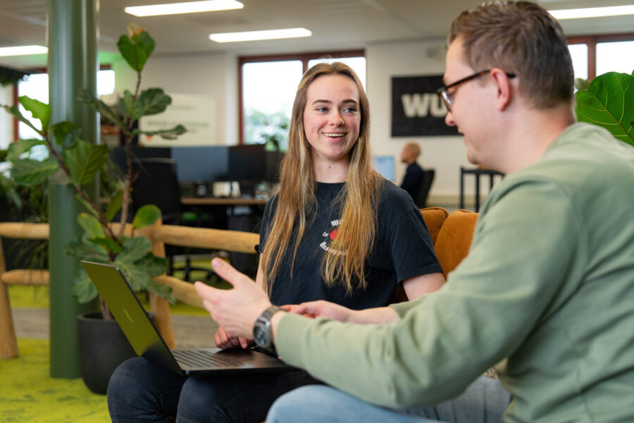 Twee collega’s lachend in gesprek over het maken van effectieve AI-prompts met de RECIPE-methode