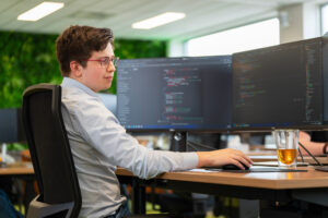 Een softwareontwikkelaar werkt aan code die bedrijfslogica omzet in concrete functionaliteit binnen een softwaresysteem.