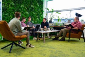 Een team van softwareontwikkelaars bespreekt bedrijfsprocessen in het moderne kantoor van Wux om functionele eisen te vertalen naar softwareoplossingen.