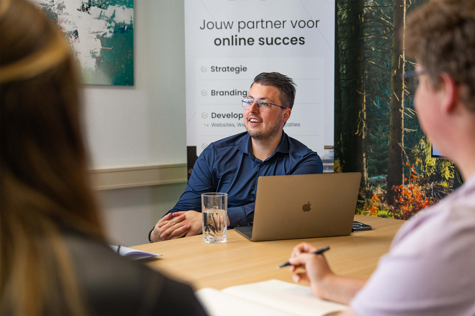 Medewerker bespreekt de mogelijkheden van een webportaal tijdens een klantoverleg, met focus op digitale strategie en online succes.
