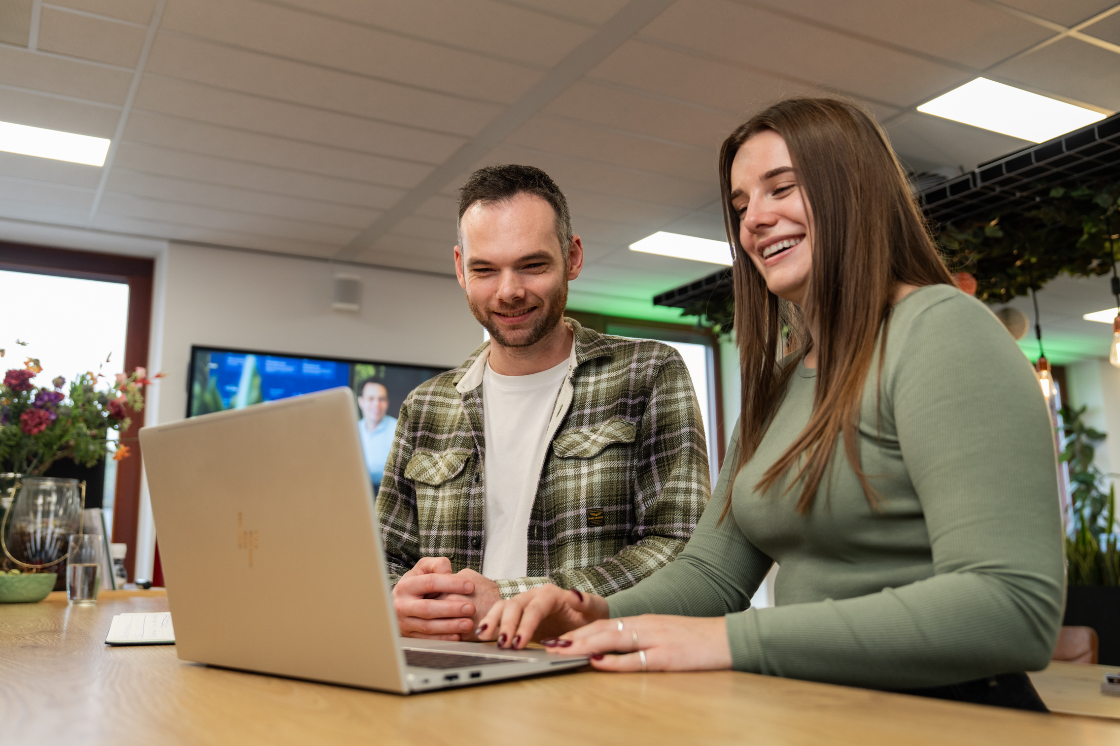 Twee collega’s werken samen achter een laptop aan een groeistrategie tijdens een gesprek in het moderne kantoor van Wux.
