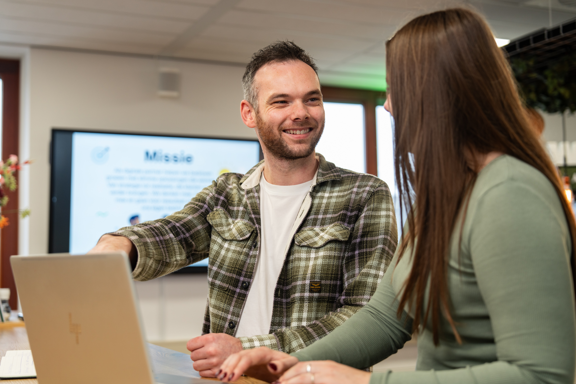 Teamleden van Wux werken samen aan SEO en online marketing aan een laptop in een inspirerende kantooromgeving.