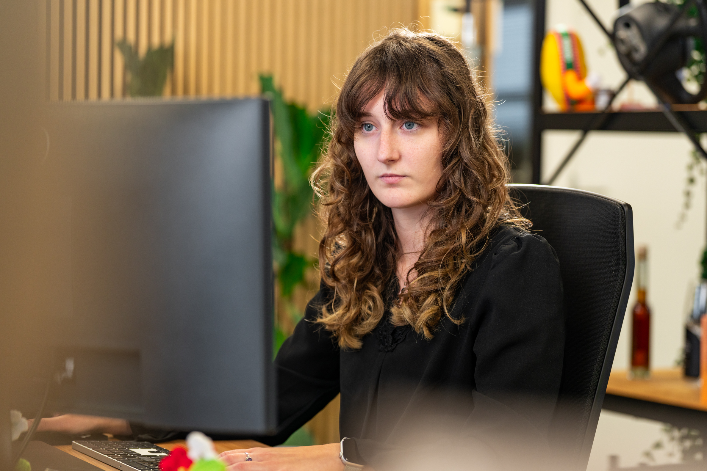 Vrouw werkt geconcentreerd achter een computerscherm aan UX/UI design in de moderne kantooromgeving van Wux.