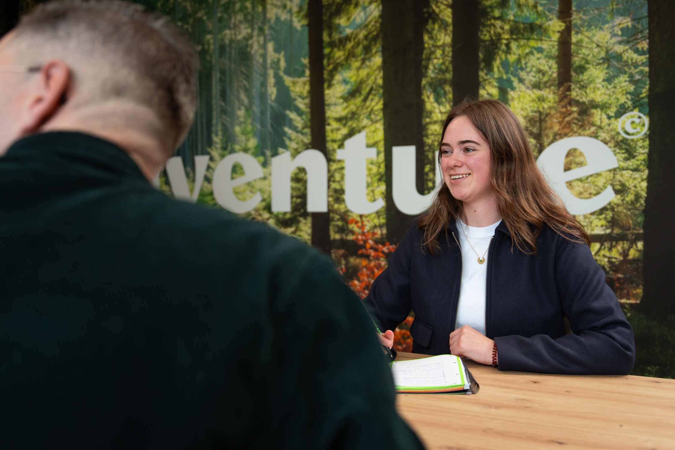 Vrouw glimlacht tijdens een overleg over een groeistrategie aan tafel met een collega.