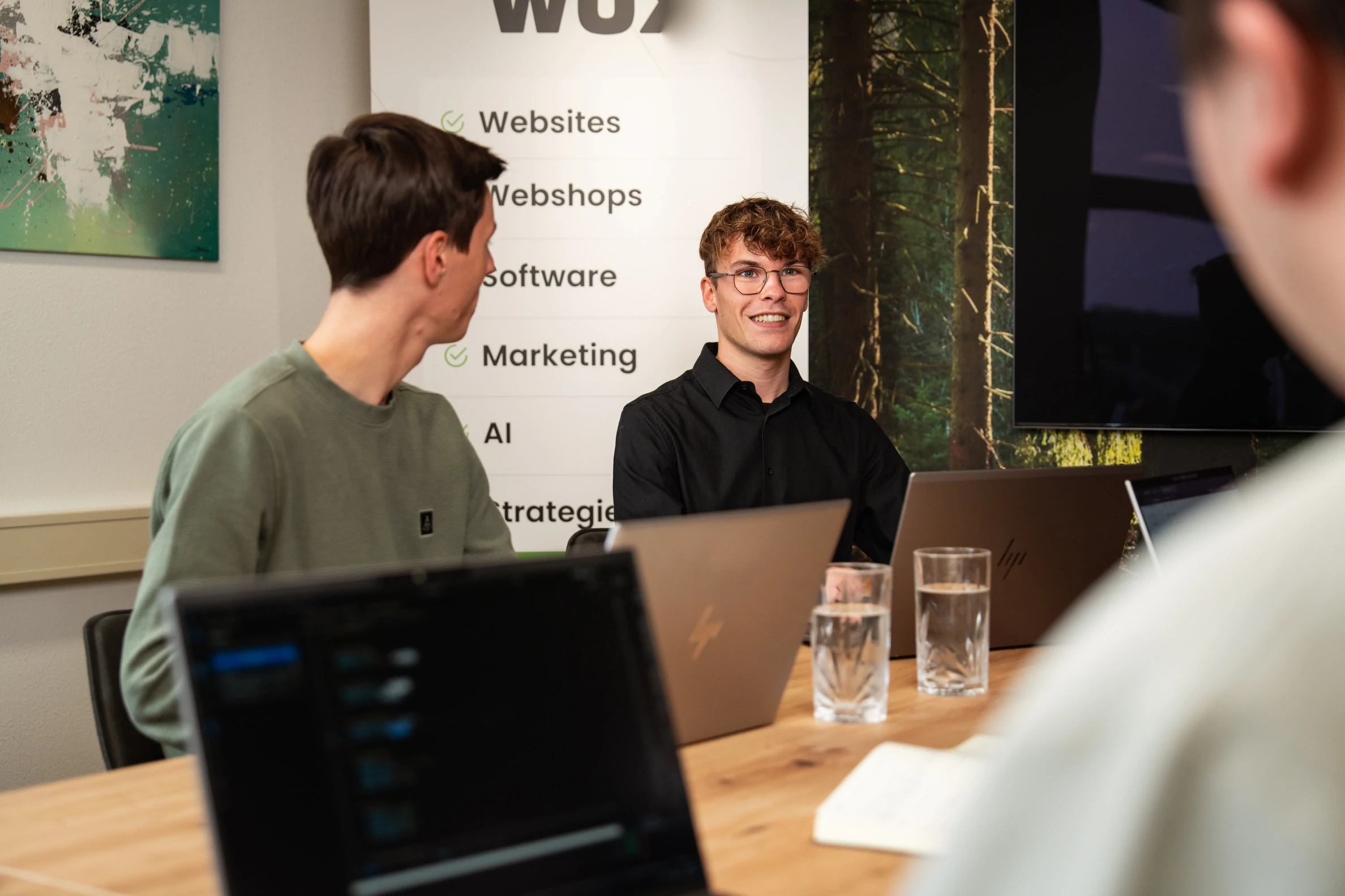 Twee collega’s bespreken een project met laptops op tafel tijdens een teamoverleg op kantoor.