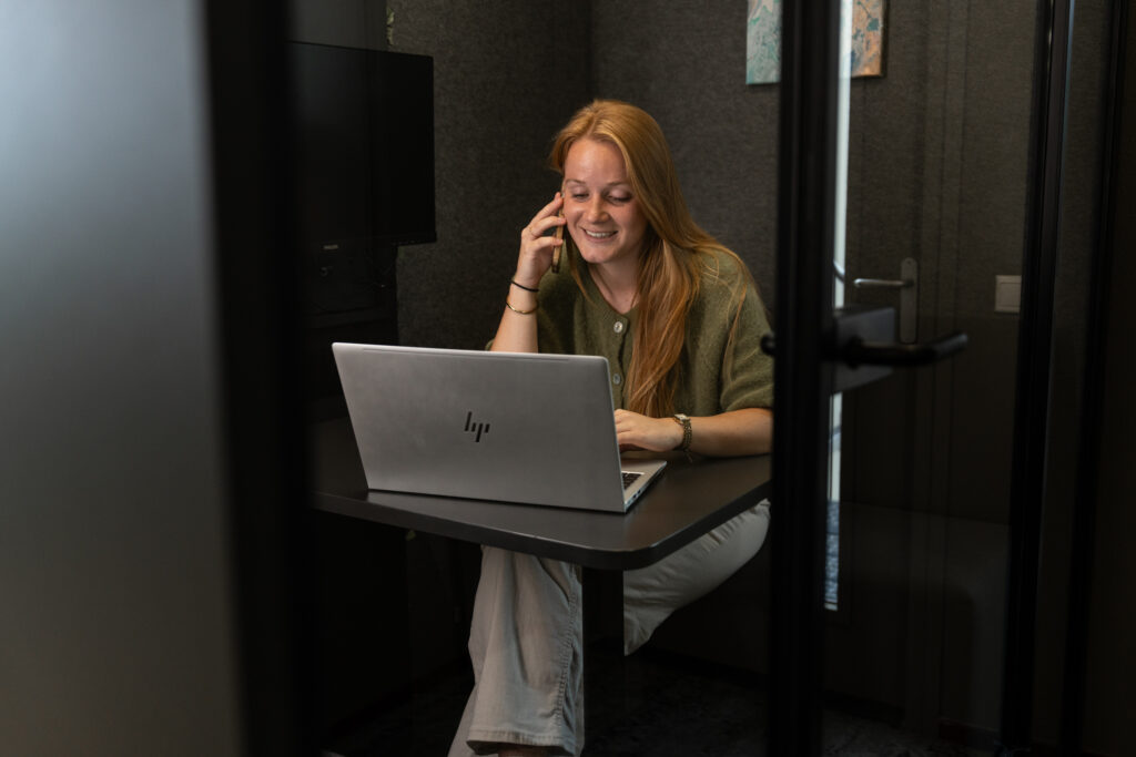 Medewerker van Wux bespreekt telefonisch een SEA-strategie met een klant terwijl ze achter haar laptop werkt.