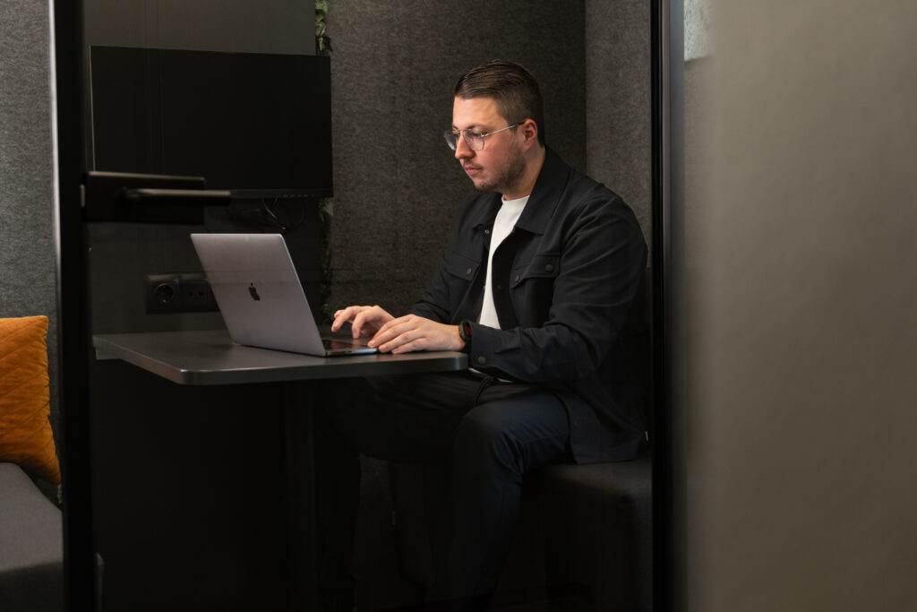 Man werkt geconcentreerd op zijn laptop in een stille werkruimte met moderne inrichting