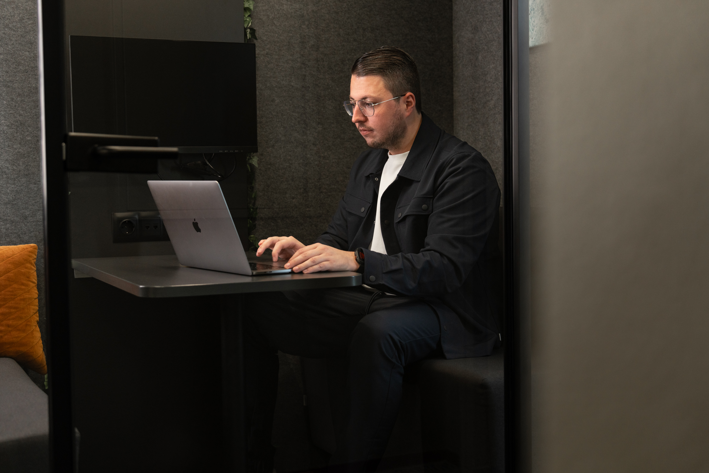 Man werkt geconcentreerd op zijn laptop in een stille werkruimte met moderne inrichting