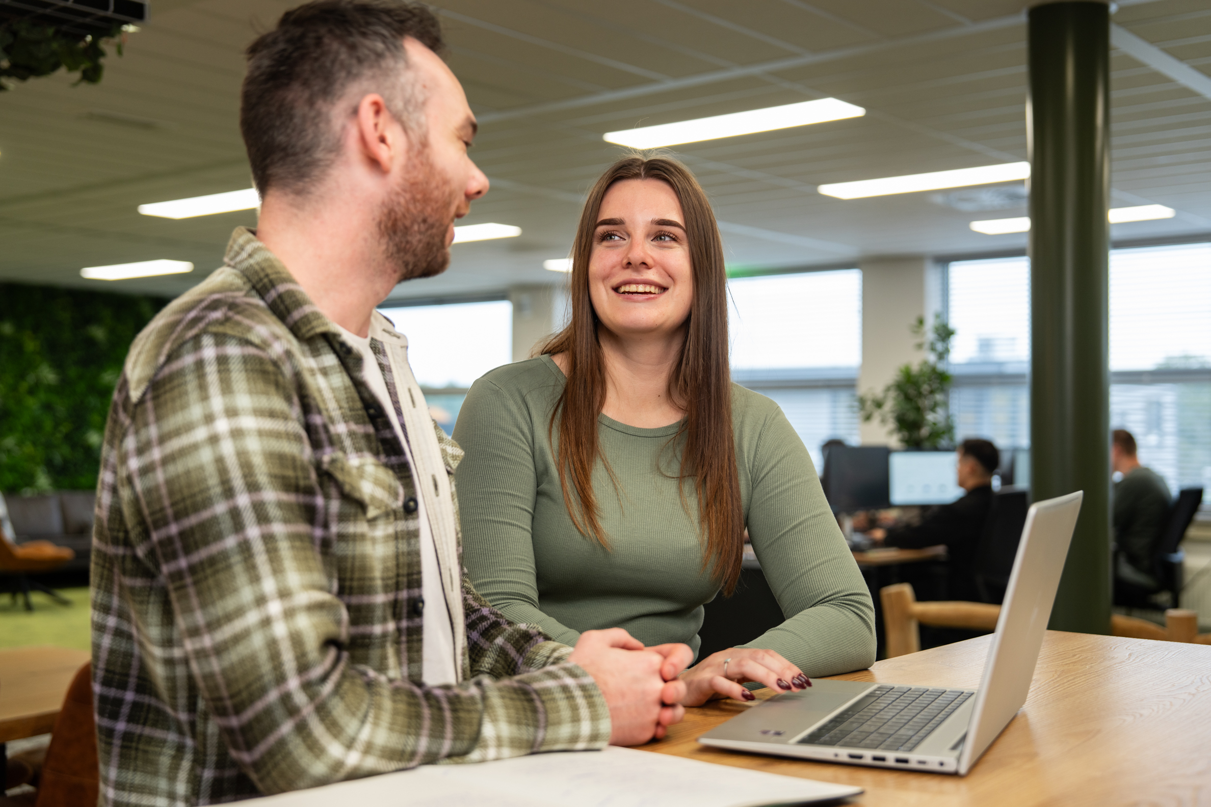 Collega’s van Wux bespreken SEA-strategieën en online groei aan een laptop in een moderne kantooromgeving.