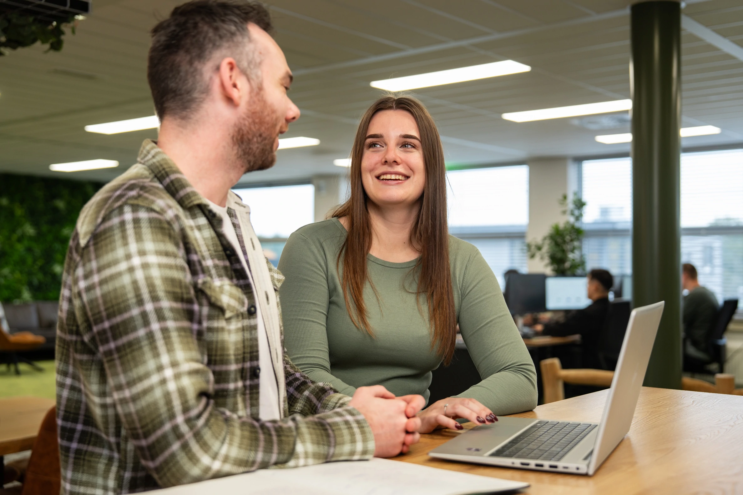 Collega’s van Wux bespreken SEA-strategieën en online groei aan een laptop in een moderne kantooromgeving.