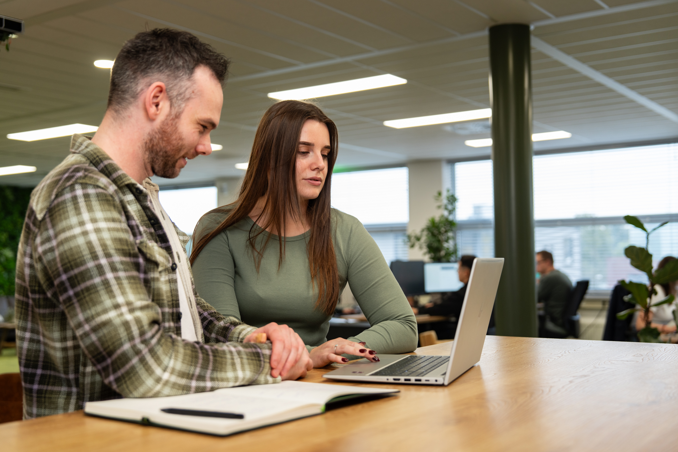 Collega’s bespreken een linkbuildingstrategie op kantoor, terwijl ze samen naar resultaten op een laptop kijken.