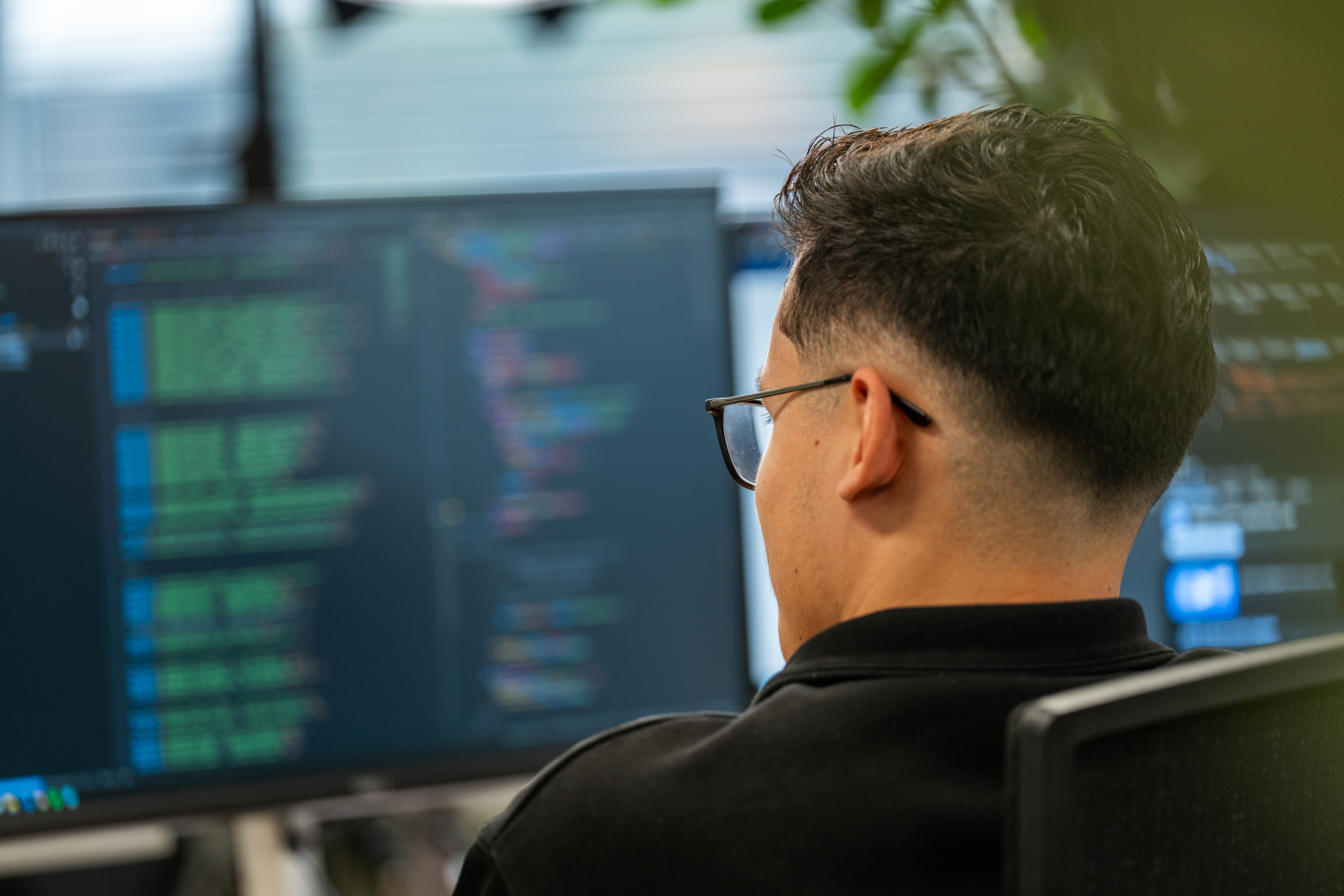 Developer van Wux werkt aan de code van een Material Requirements Planning systeem op kantoor.