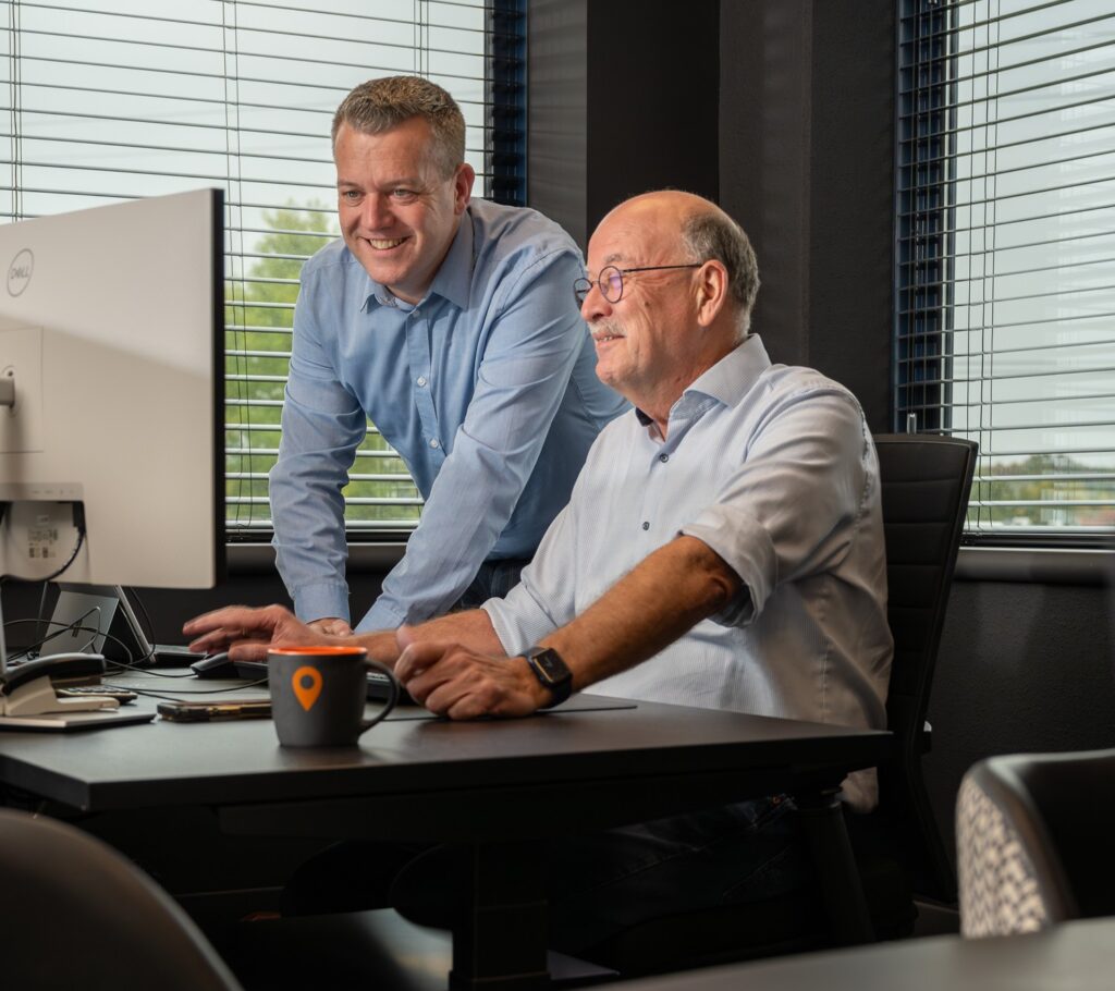 Twee professionals van ADA ICT werken met een glimlach samen achter een beeldscherm.