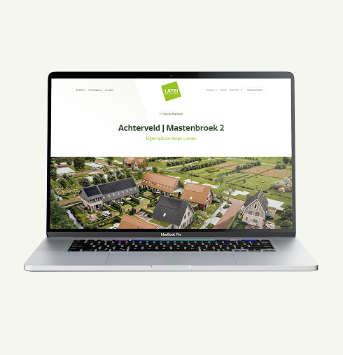 Mock-up van de LATEI website op een laptopscherm. De getoonde pagina is van het project 'Achterveld | Mastenbroek 2' met de subtitel 'Eigentijds én dorps wonen'. Daaronder staat een vogelvluchtimpressie van de nieuwe woonwijk met huizen voorzien van zonnepanelen, gelegen in een landelijke, groene omgeving.