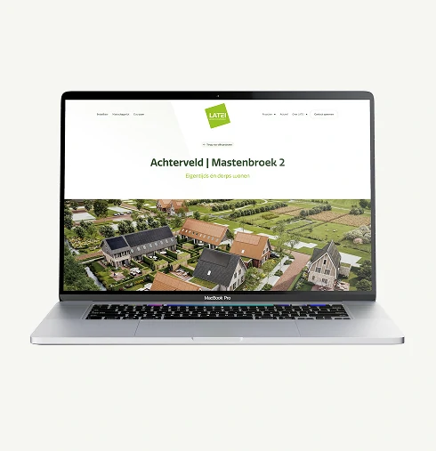 Mock-up van de LATEI website op een laptopscherm. De getoonde pagina is van het project 'Achterveld | Mastenbroek 2' met de subtitel 'Eigentijds én dorps wonen'. Daaronder staat een vogelvluchtimpressie van de nieuwe woonwijk met huizen voorzien van zonnepanelen, gelegen in een landelijke, groene omgeving.